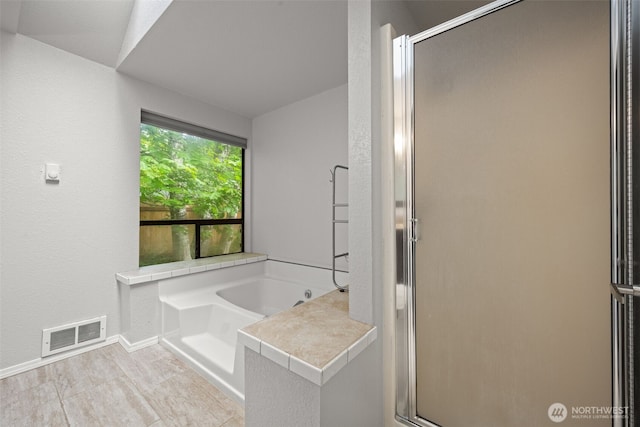 full bathroom with a stall shower, a garden tub, baseboards, and a textured wall
