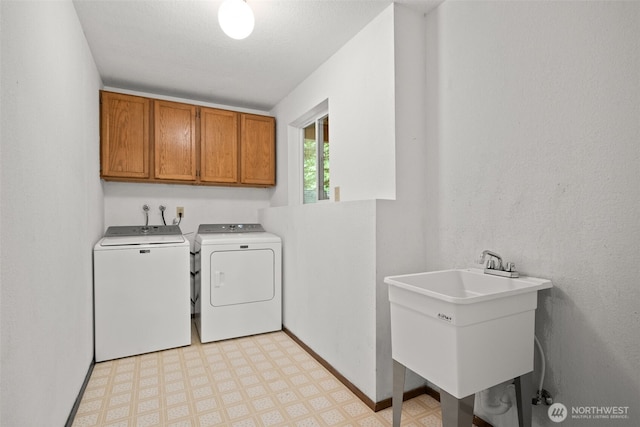 washroom featuring washing machine and dryer, cabinet space, light floors, and baseboards