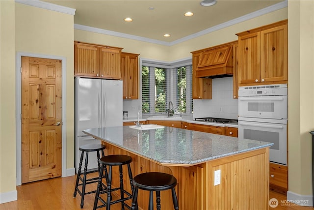 13901 Twin Lakes Dr E, Graham, WA 98338 - kitchen with white double oven, a sink, light wood-type flooring, decorative backsplash, and a center island with sink