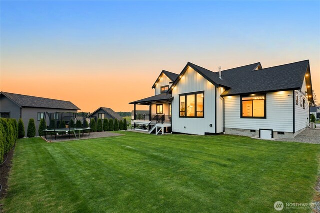 1750 Farmview Ter, Lynden, WA 98264 - back of house with a trampoline, a lawn, board and batten siding, a wooden deck, and a shingled roof