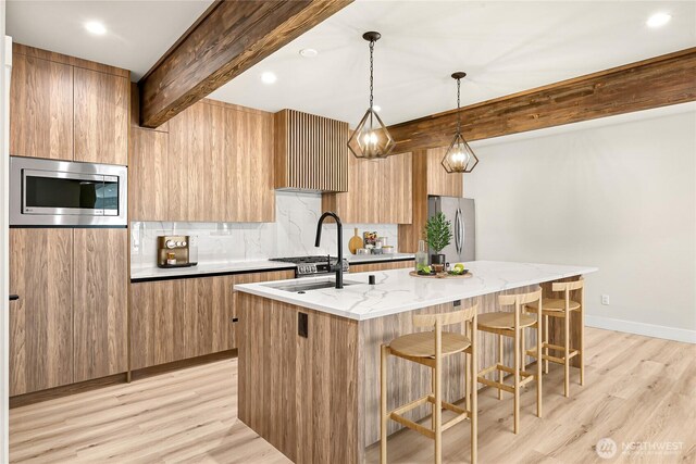 1750 Farmview Ter, Lynden, WA 98264 - kitchen featuring appliances with stainless steel finishes, modern cabinets, beamed ceiling, a center island with sink, and light wood-type flooring