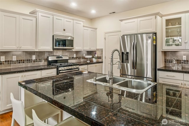 kitchen featuring stainless steel appliances, a sink, tile counters, white cabinetry, and recessed lighting