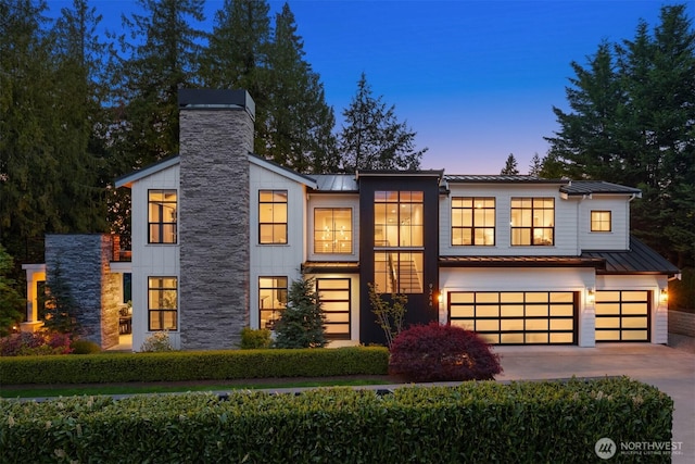 contemporary home featuring a standing seam roof, an attached garage, and metal roof