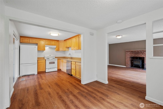 20302 52nd Ave W, Lynnwood, WA 98036 - kitchen with white appliances, under cabinet range hood, light countertops, dark wood finished floors, and a wood stove