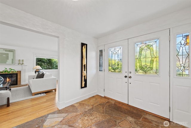 foyer with a tile fireplace, stone finish floors, and baseboards