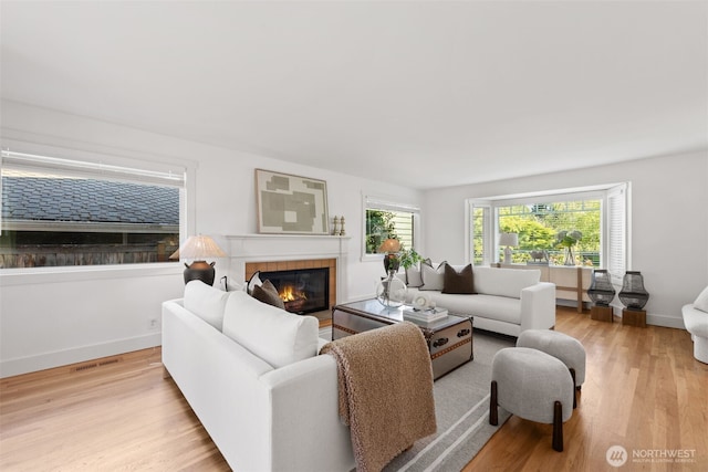 living room with wood finished floors, a tile fireplace, and baseboards