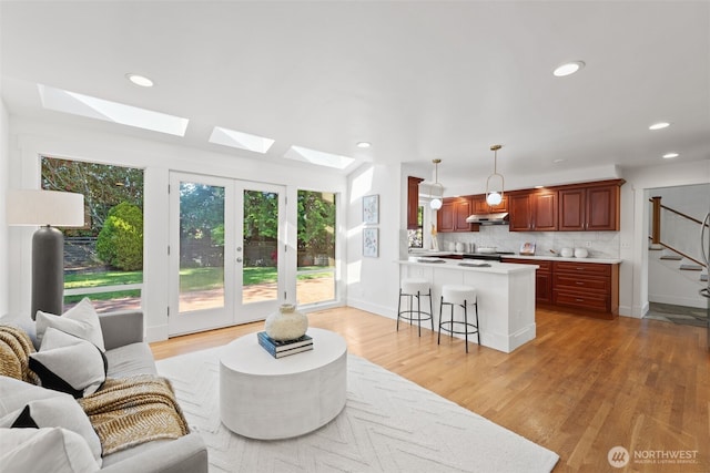 living room featuring recessed lighting, light wood-style flooring, a skylight, stairway, and baseboards