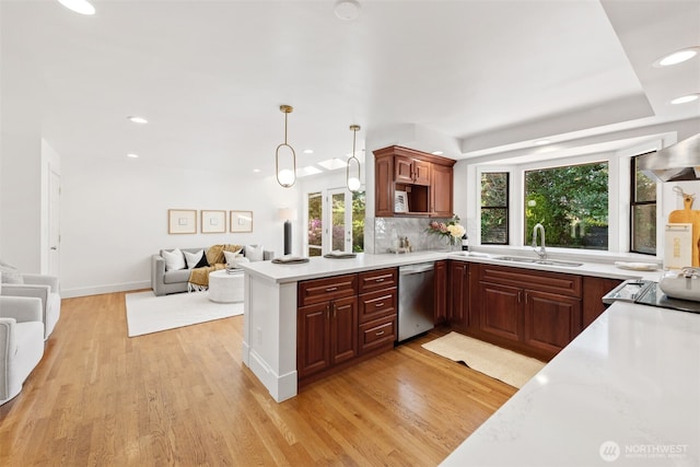 kitchen with dishwasher, a sink, open floor plan, light wood finished floors, and light countertops