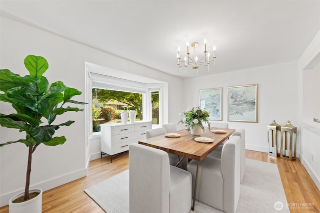 dining space with light wood-style floors, a chandelier, and baseboards