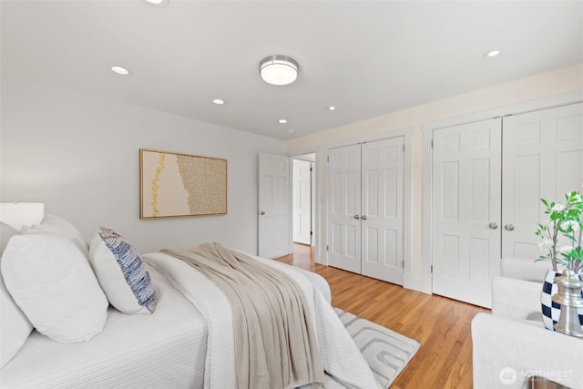 bedroom with two closets, light wood-style floors, and recessed lighting