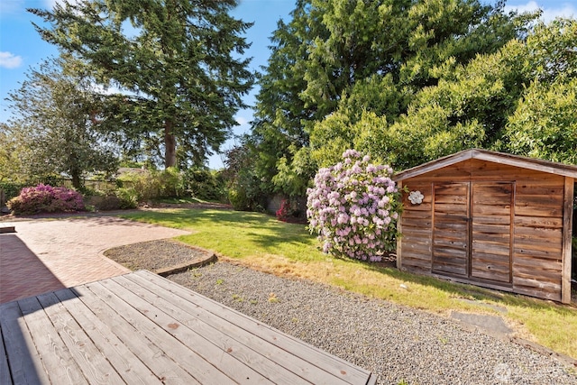 wooden terrace featuring a storage shed, an outbuilding, and a patio