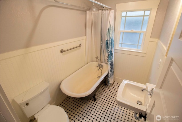 231 Karr Ave, Hoquiam, WA 98550 - full bathroom featuring wainscoting, a sink, a tub to relax in, toilet, and a decorative wall