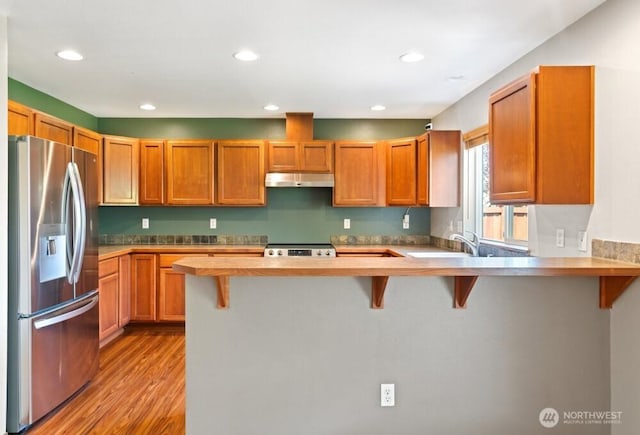 167 Wind River Rd, Chehalis, WA 98532 - kitchen with stainless steel appliances, under cabinet range hood, a peninsula, light wood-type flooring, and a breakfast bar area