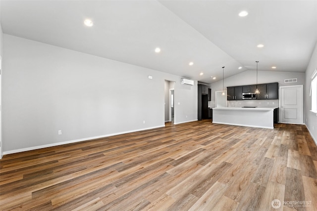 41 E Compass Ln, Allyn, WA 98524 - unfurnished living room with lofted ceiling, a wall mounted air conditioner, light wood finished floors, baseboards, and recessed lighting
