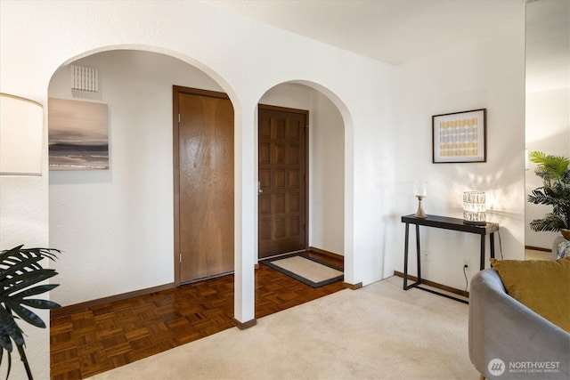 foyer entrance with baseboards and arched walkways