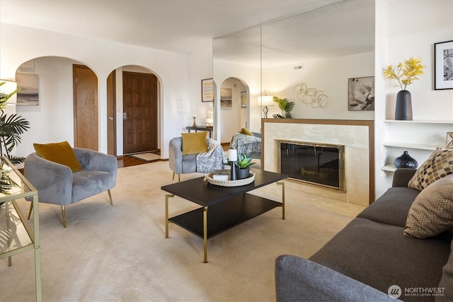 carpeted living area with arched walkways and a fireplace