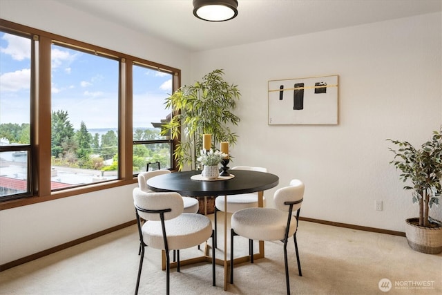 dining space with plenty of natural light, light colored carpet, and baseboards