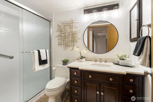 bathroom featuring toilet, a shower stall, and vanity