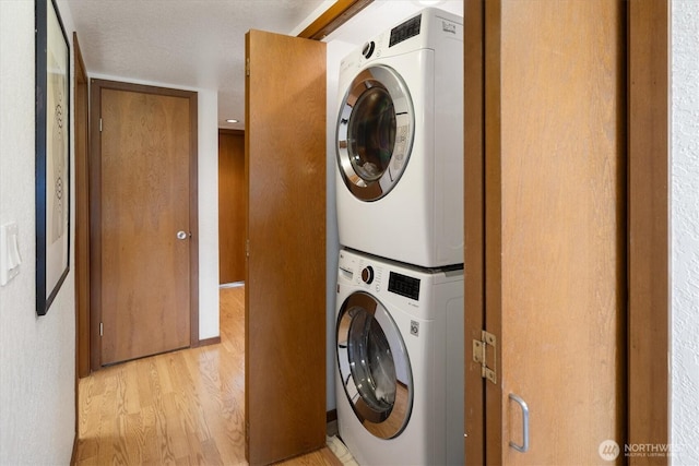 clothes washing area featuring stacked washer / dryer and light wood-type flooring