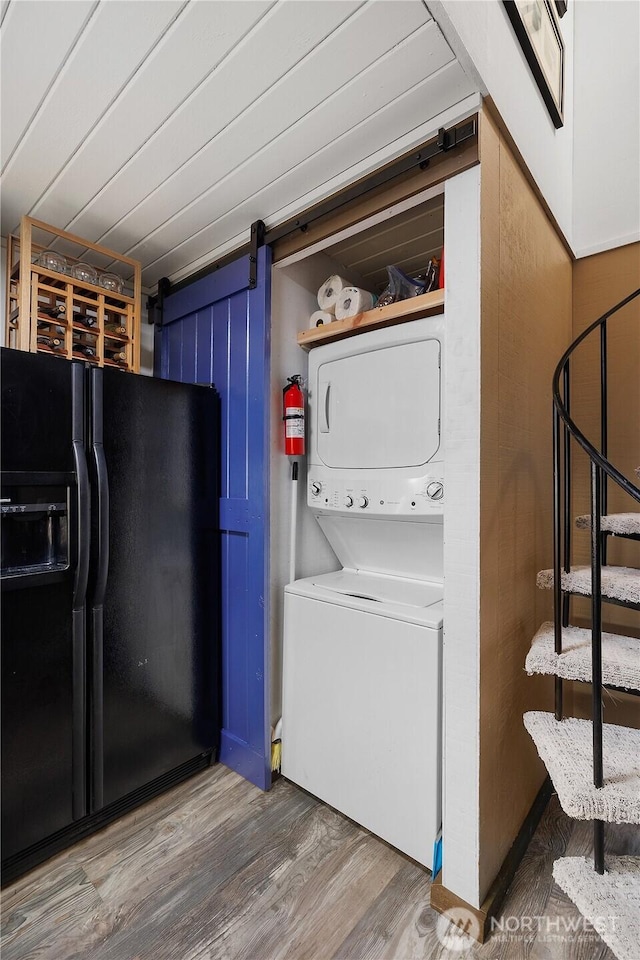 735 E Promontory Rd, Shelton, WA 98584 - laundry area featuring stacked washer / dryer, a barn door, and wood finished floors