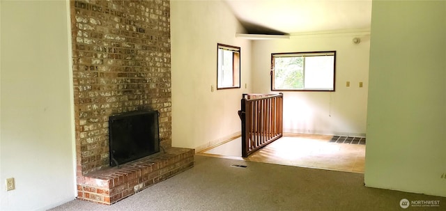 22930 115th Ave SW, Vashon, WA 98070 - unfurnished living room with carpet flooring, a brick fireplace, baseboards, and lofted ceiling