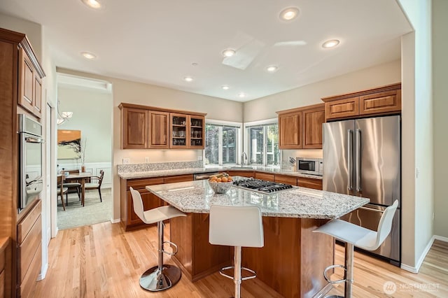 922 Chelan Ave NE, Renton, WA 98059 - kitchen with appliances with stainless steel finishes, a sink, brown cabinets, a breakfast bar area, and a kitchen island