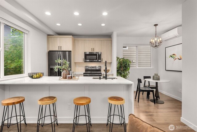 919 N 103rd St Unit A, Seattle, WA 98133 - kitchen with appliances with stainless steel finishes, a wall unit AC, light brown cabinetry, recessed lighting, and a kitchen bar