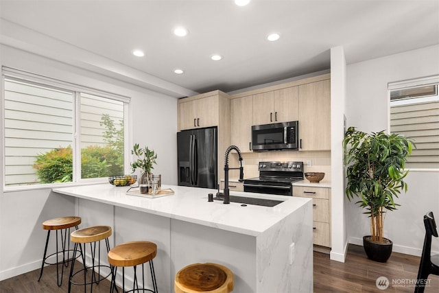 919 N 103rd St Unit A, Seattle, WA 98133 - kitchen with black appliances, a sink, light brown cabinetry, recessed lighting, and a kitchen breakfast bar