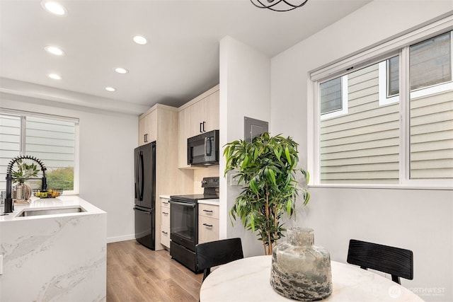 919 N 103rd St Unit A, Seattle, WA 98133 - kitchen featuring black appliances, recessed lighting, light wood-type flooring, a sink, and light stone counters
