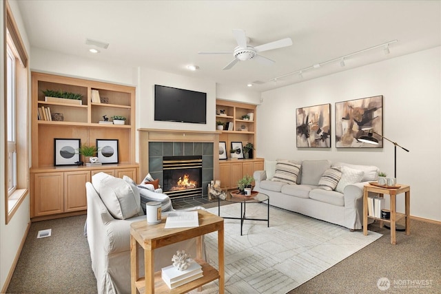 living area with light carpet, a tiled fireplace, ceiling fan, baseboards, and recessed lighting