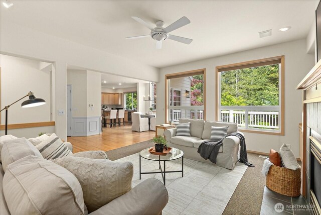 living room featuring ceiling fan, recessed lighting, a glass covered fireplace, and light wood-style floors