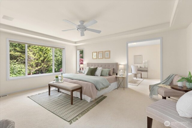 carpeted bedroom featuring a tray ceiling and ceiling fan