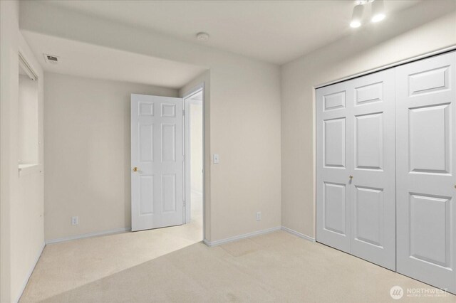 unfurnished bedroom with light carpet, baseboards, and a closet