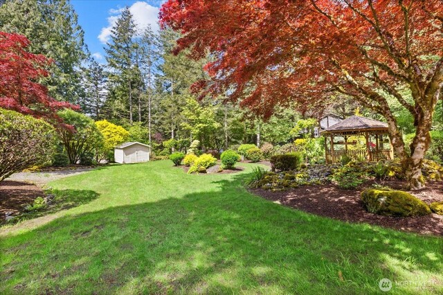 view of grassy yard with a gazebo, an outdoor structure, and a storage shed