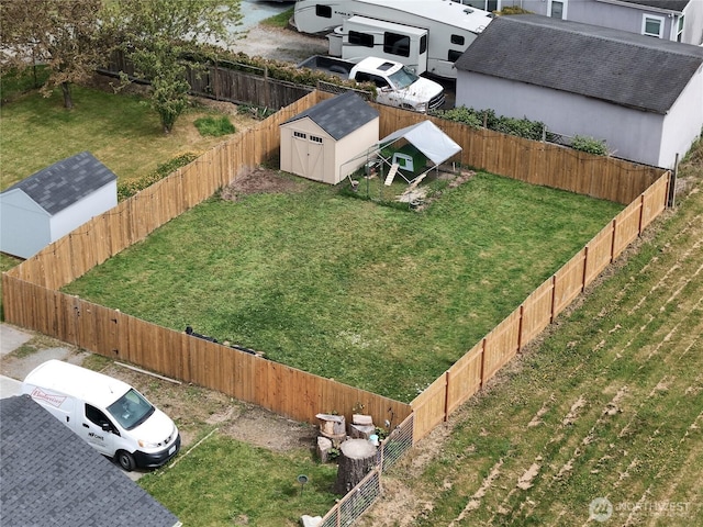 fenced backyard featuring a storage shed and an outbuilding