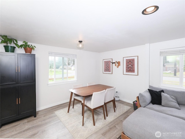 dining space with light wood-type flooring and baseboards
