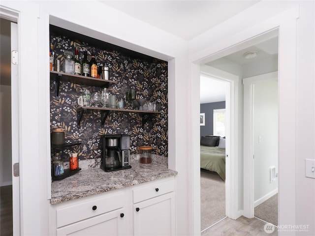 indoor dry bar with baseboards, light carpet, and light wood-style floors