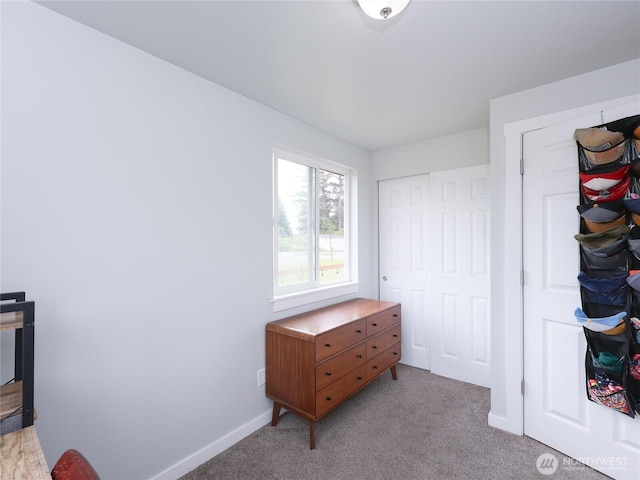 bedroom featuring light colored carpet, baseboards, and a closet