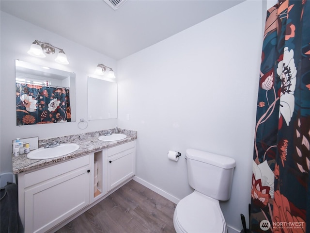 bathroom featuring wood finished floors, toilet, double vanity, baseboards, and a shower with curtain