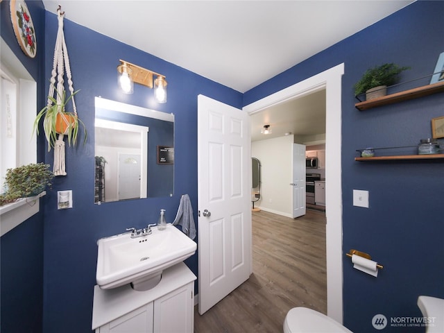 bathroom with wood finished floors, vanity, toilet, and baseboards