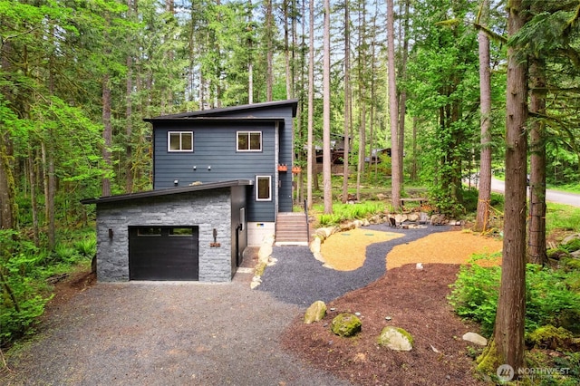 7467 Canyon View Dr, Deming, WA 98244 - view of front facade featuring gravel driveway, an attached garage, and a forest view