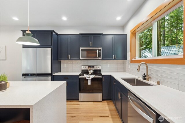 7467 Canyon View Dr, Deming, WA 98244 - kitchen with stainless steel appliances, a sink, light wood-style flooring, light countertops, and decorative backsplash