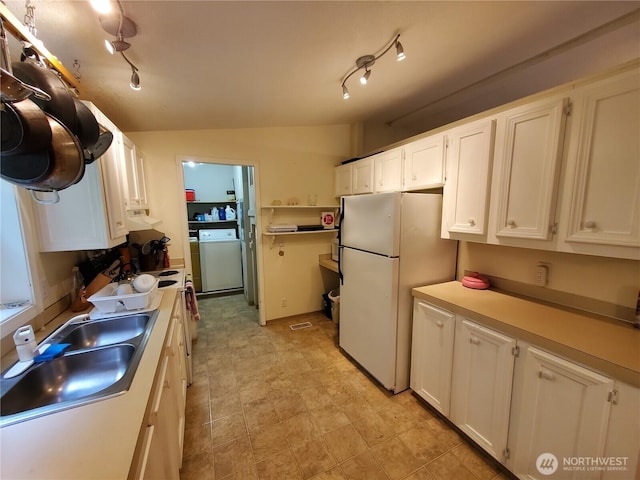 669 Duck Lake Dr NE, Ocean Shores, WA 98569 - kitchen featuring washer / clothes dryer, freestanding refrigerator, a sink, white cabinets, and light countertops