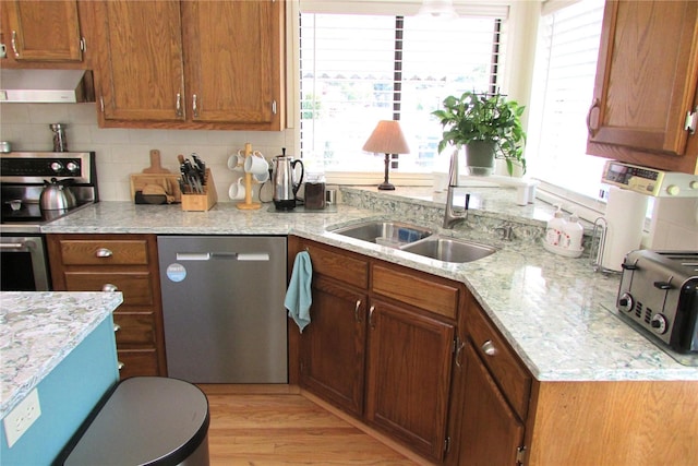 1427 100th St SW Unit 149, Everett, WA 98204 - kitchen featuring appliances with stainless steel finishes, a sink, wall chimney exhaust hood, brown cabinets, and light stone counters