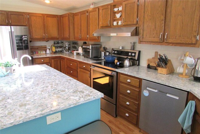 1427 100th St SW Unit 149, Everett, WA 98204 - kitchen featuring appliances with stainless steel finishes, wall chimney range hood, brown cabinetry, light wood-type flooring, and a sink