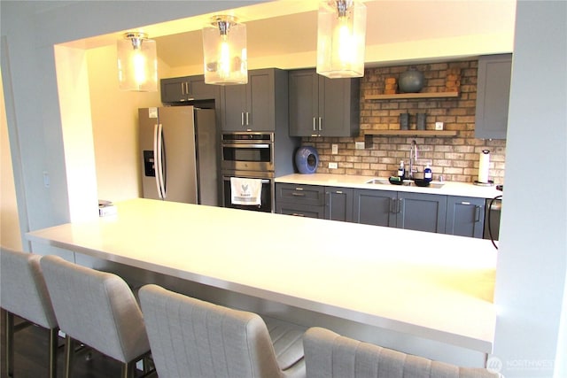 1427 100th St SW Unit 149, Everett, WA 98204 - kitchen featuring stainless steel appliances, a sink, gray cabinetry, a kitchen bar, and backsplash