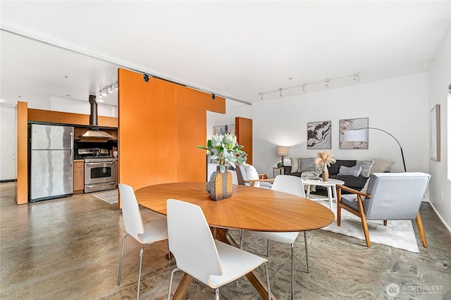 dining area with track lighting and finished concrete floors