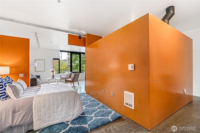 bedroom with track lighting and wood finished floors