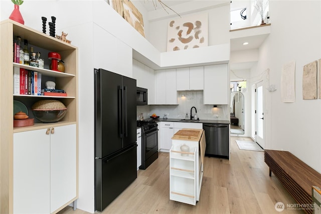 916NW 56th St Unit G, Seattle, WA 98107 - kitchen with black appliances, a sink, a high ceiling, white cabinetry, and light wood-style floors