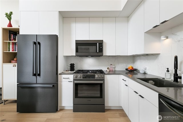 916NW 56th St Unit G, Seattle, WA 98107 - kitchen featuring appliances with stainless steel finishes, a sink, white cabinetry, and tasteful backsplash